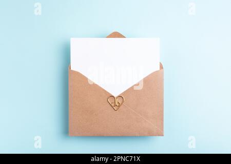 White paper card in kraft envelope. Top view, place for text. Stock Photo