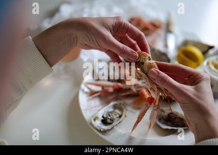 Woman cleaning prawns above table full of fresh seafood with oyster and shrimp from fish market Stock Photo