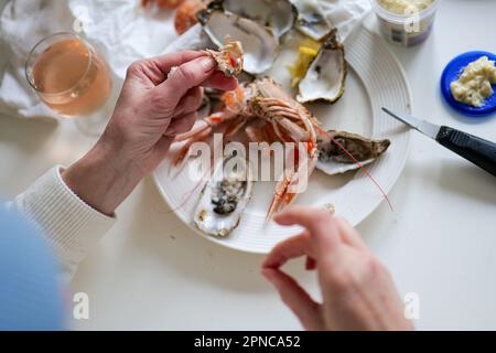 Woman cleaning prawns above table full of fresh seafood with oyster and shrimp from fish market Stock Photo