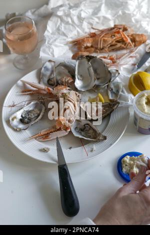 Woman opening prawns above table full of fresh seafood with oysters and prawns and lobster from fish market Stock Photo