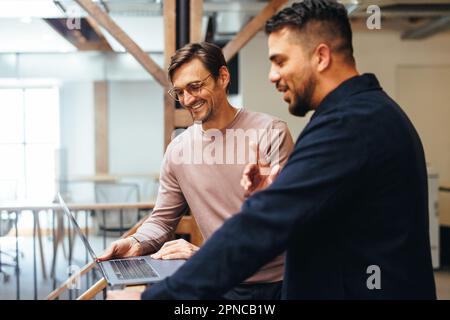 business men video calling their clients on a laptop in an office. Two business professionals joining an online meeting. Networking and making busines Stock Photo