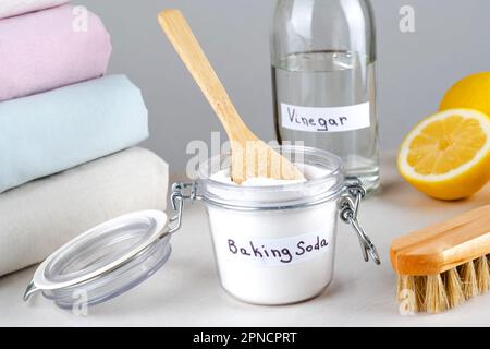 Eco friendly natural cleaners baking soda, vinegar, lemon and clothing on a white table. Stock Photo