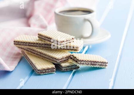 Sweet chocolate wafer and coffee cup on the blue table. Stock Photo