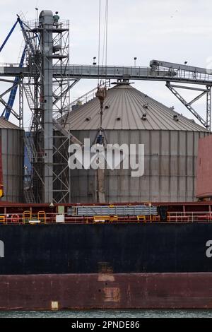 Loading sand onto a cargo barge in a seaport close-up Stock Photo