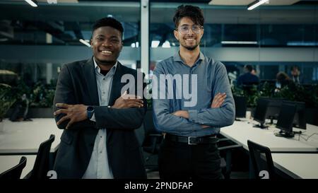 Multiracial business colleagues smiling diverse men arabian and african businessmen co-workers employees stand in office together posing arms crossed Stock Photo