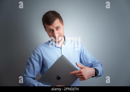 Good-looking middle-aged businessman holding an Apple laptop. Stock Photo