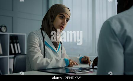 Muslim arabian woman young female doctor therapist write medical prescription recipe for sick patient writing notes filling checklist illness symptoms Stock Photo