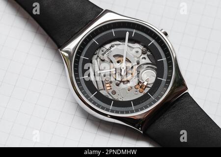 Biel, Switzerland - October 28, 2021: Swiss made quartz Black Skeleton wrist watch by Swatch is on a white background, close-up photo, top view Stock Photo