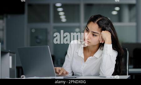 Sad bored lazy young woman typing on laptop tired unmotivated businesswoman office worker feels fatigue from working at computer suffers from overwork Stock Photo