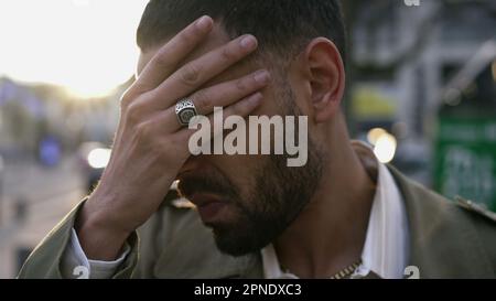 Portrait of a stressed Arab young man standing in stress feeling worry and anxiety. One Middle Eastern male person suffering from mental distress and Stock Photo