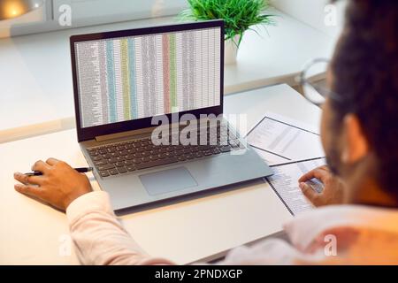 African American business accountant working with financial sheets on laptop computer Stock Photo