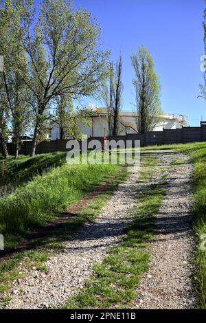 Path  on an embankment next to a boundary wall of an industrial complex in a forest Stock Photo