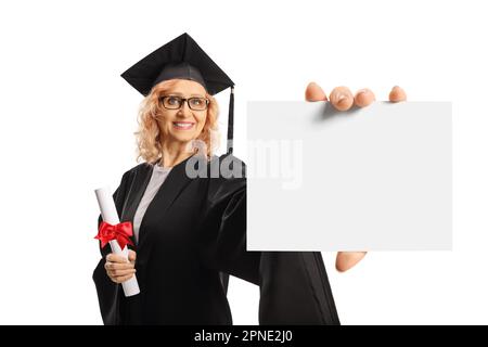Mature woman in a graduation gown holding a diploma and showing blank card isolated on white background Stock Photo