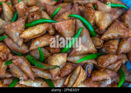 Freshly cooked samosa ready for serving with a fresh green chilli on top. Stock Photo