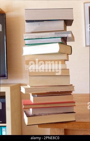 A High Stack Of Books On The Edge Of A Table Stock Photo