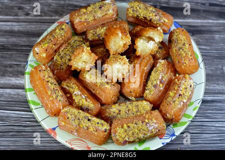 Tulumba, Bamiyeh or Balah El Sham stuffued with whipped cream and covered with pistachios and nuts, deep fried batter dessert soaked in syrup, similar Stock Photo