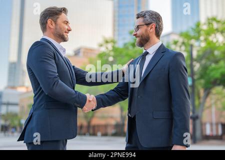 American businessman shaking hands with partner. Two businessmen shaking hands outdoors. Shaking hands. Management strategy. Handshake between two bus Stock Photo