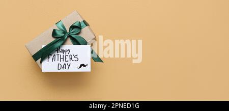 Paper with text HAPPY FATHER'S DAY and gift on beige background with space for text Stock Photo
