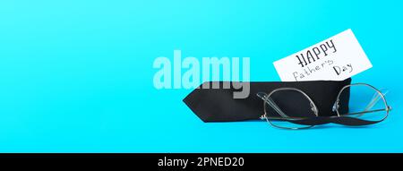Paper with text HAPPY FATHER'S DAY, necktie and glasses on light blue background with space for text Stock Photo