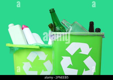Trash bins with different garbage on green background, closeup Stock Photo