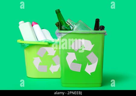 Trash bins with different garbage on green background Stock Photo