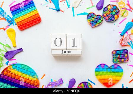 Cube calendar with date 01 JUNE and pop it toys on white background. Children's Day celebration Stock Photo