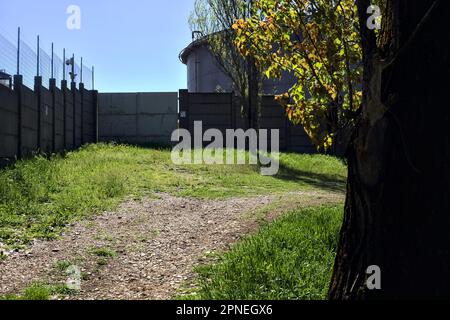 Path  on an embankment next to a boundary wall of an industrial complex in a forest Stock Photo