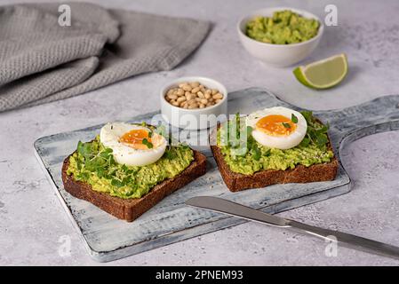 Food photography of sandwich with rye bread, egg, avocado, cress salad, pine nuts, lime, toast, breakfast, dieting Stock Photo