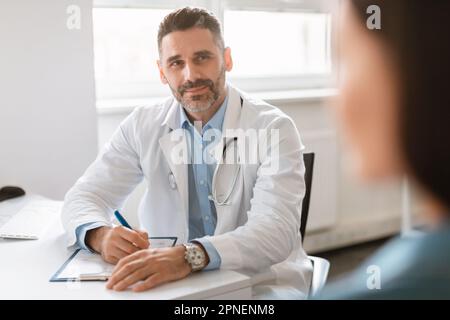 General practitioner appointment. Confident male doctor talking to female patient, discussing diagnosis and treatment Stock Photo