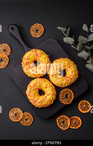 Delicious fresh donuts in yellow glaze with lemon flavor filling on textured concrete background Stock Photo