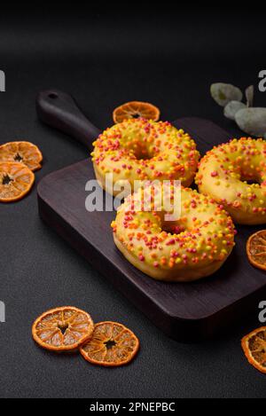 Delicious fresh donuts in yellow glaze with lemon flavor filling on textured concrete background Stock Photo