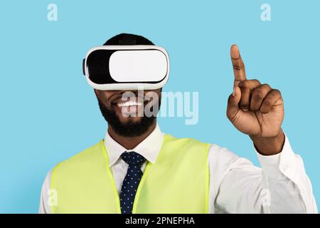 Black Builder Man Using VR Glasses And Touching Air With Finger Stock Photo