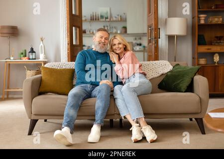 Loving Senior Couple Embracing Posing In Living Room At Home Stock Photo