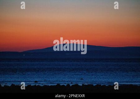 Heysham Lancashire, U Nited Kingdom. 18th Apr, 2023. Black Combe in cumbria back light by this evenings aftre glow seen from Morecambe Credit: PN News/Alamy Live News Stock Photo