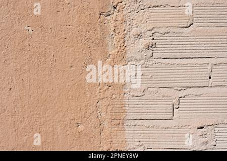 A cheap brick wall painted in a light color next to a smooth one in a slightly darker color Stock Photo
