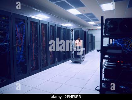 Female technician using laptop in server room Stock Photo