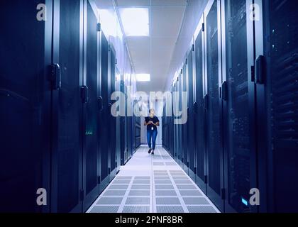 Female technician walking in server room Stock Photo