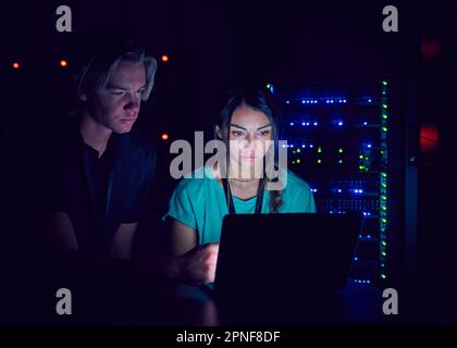 Technicians using laptop in server room Stock Photo