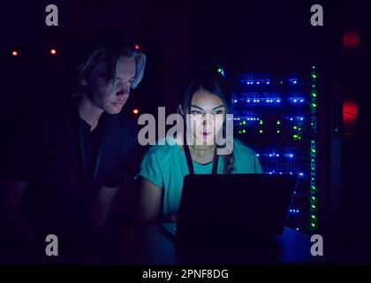 Technicians using laptop in server room Stock Photo