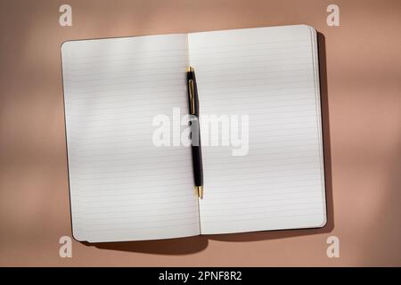 Pen in open notebook on brown background Stock Photo