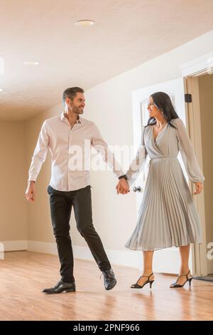 Couple holding hands and walking in to new apartment Stock Photo