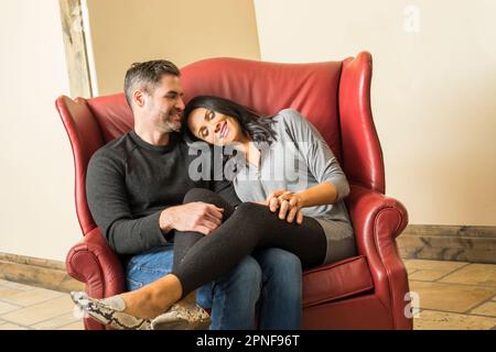 Cheerful couple relaxing on armchair together Stock Photo