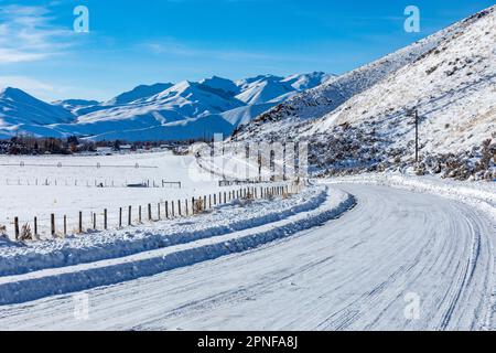 United States, Idaho, Bellevue, Snow covered rural road with mountains in distance Stock Photo