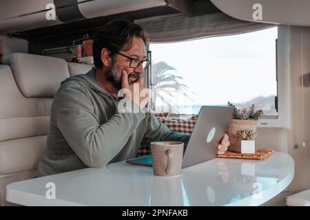 Man sitting in mobile home and working on laptop Stock Photo