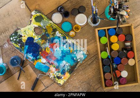 High angle view of brushes, pallete, oils, acrylics and other elements of a painter artist. Art workshop. Background. Stock Photo