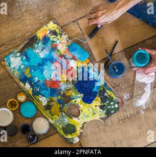 High angle view of brushes, pallete, oils, acrylics and other elements of a painter artist. Art workshop. Background. Stock Photo