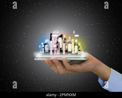 A hand holding a smartphone with virtual Smart City on it, night scene. The city is equipped with smart service and all kinds of online activity icons Stock Photo