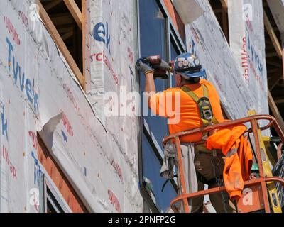 Construction workers installing window in highrise apartment building under construction. Stock Photo