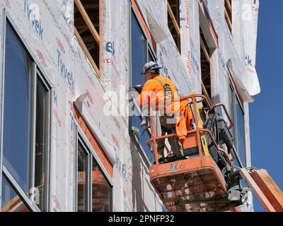 Construction workers installing window in highrise apartment building under construction. Stock Photo