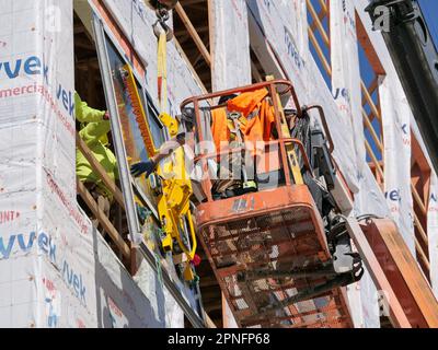 Construction workers installing window in highrise apartment building under construction. Stock Photo